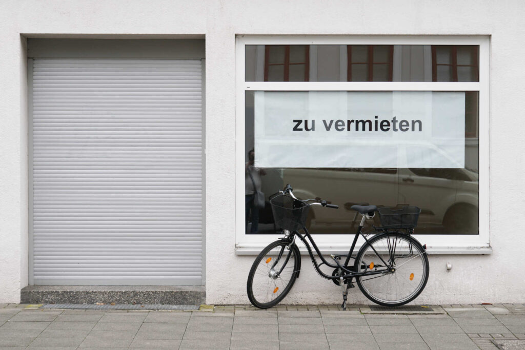 Leerstehendes Ladenlokal, vor dem ein Fahrrad steht. Schild "Zu vermieten" im Schaufenster.