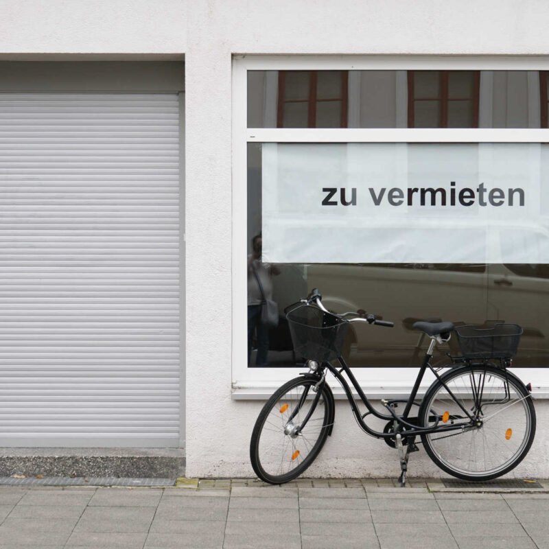 Leerstehendes Ladenlokal, vor dem ein Fahrrad steht. Schild "Zu vermieten" im Schaufenster.
