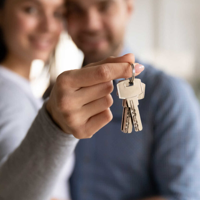 Ein Paar hält die Schlüssel ihres Eigenheims in den Händen.