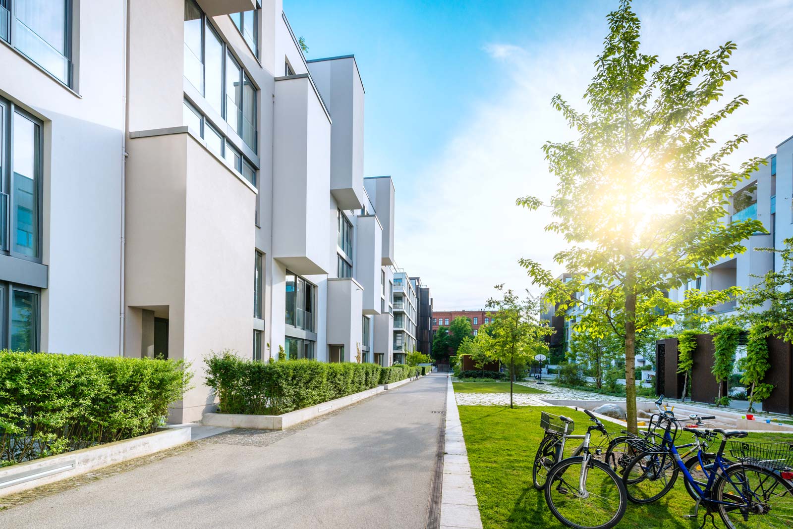 Moderne Wohnhaus-Siedlung im Gegenlicht, Grünfläche mit abgestellten Fahrrädern