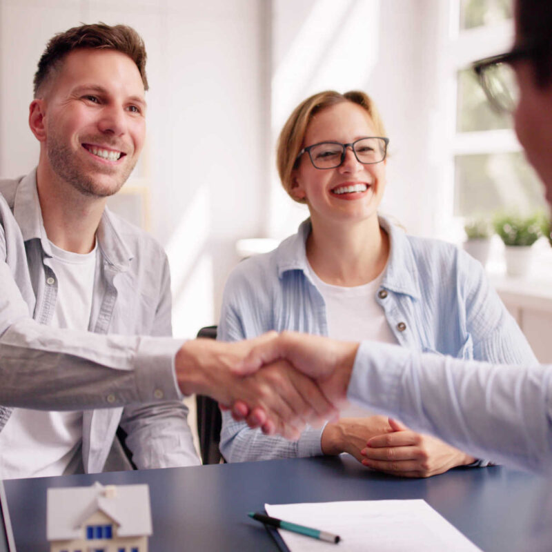 Junges Paar schüttelt Notar nach Vertragsunterzeichnung die Hand